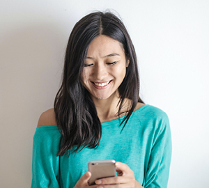 Young woman smiling while looking at her cell phone.