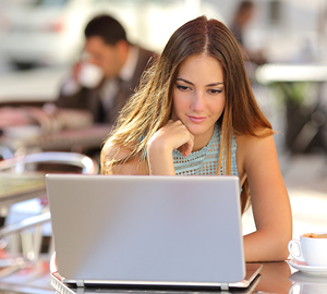 Young female with her hand on her chin looking at her laptop.