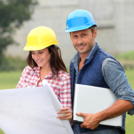 Man and woman wearing hard hats holding blueprints