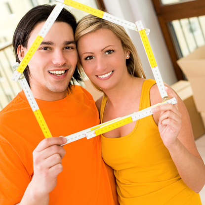 Young couple holding a ruler in the shape of a house.