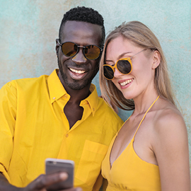 Couple wearing sunglasses looking at a mobile phone