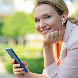 Woman smiling while holding a cell phone in the park