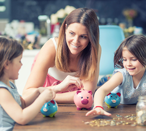 Young mother with her two children smiling while putting coins into their piggy banks.