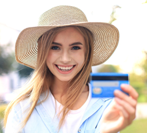Young girl in a straw hat smiling while holding her debit card